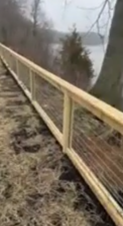 Custom wood and wire fence running along a lakeside property