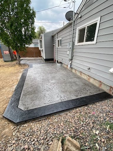 Stamped concrete patio with charcoal border along a home