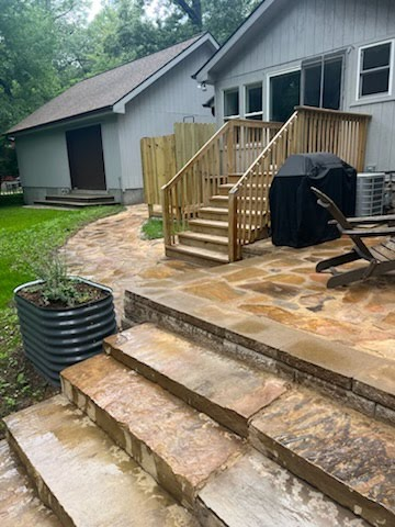 Flagstone patio with raised planter and steps leading to a backyard deck